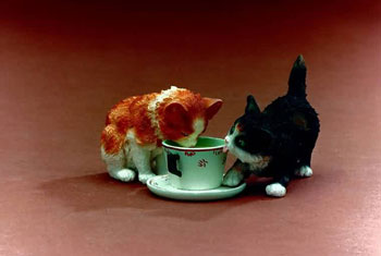 Two cat figures beside a green cup
